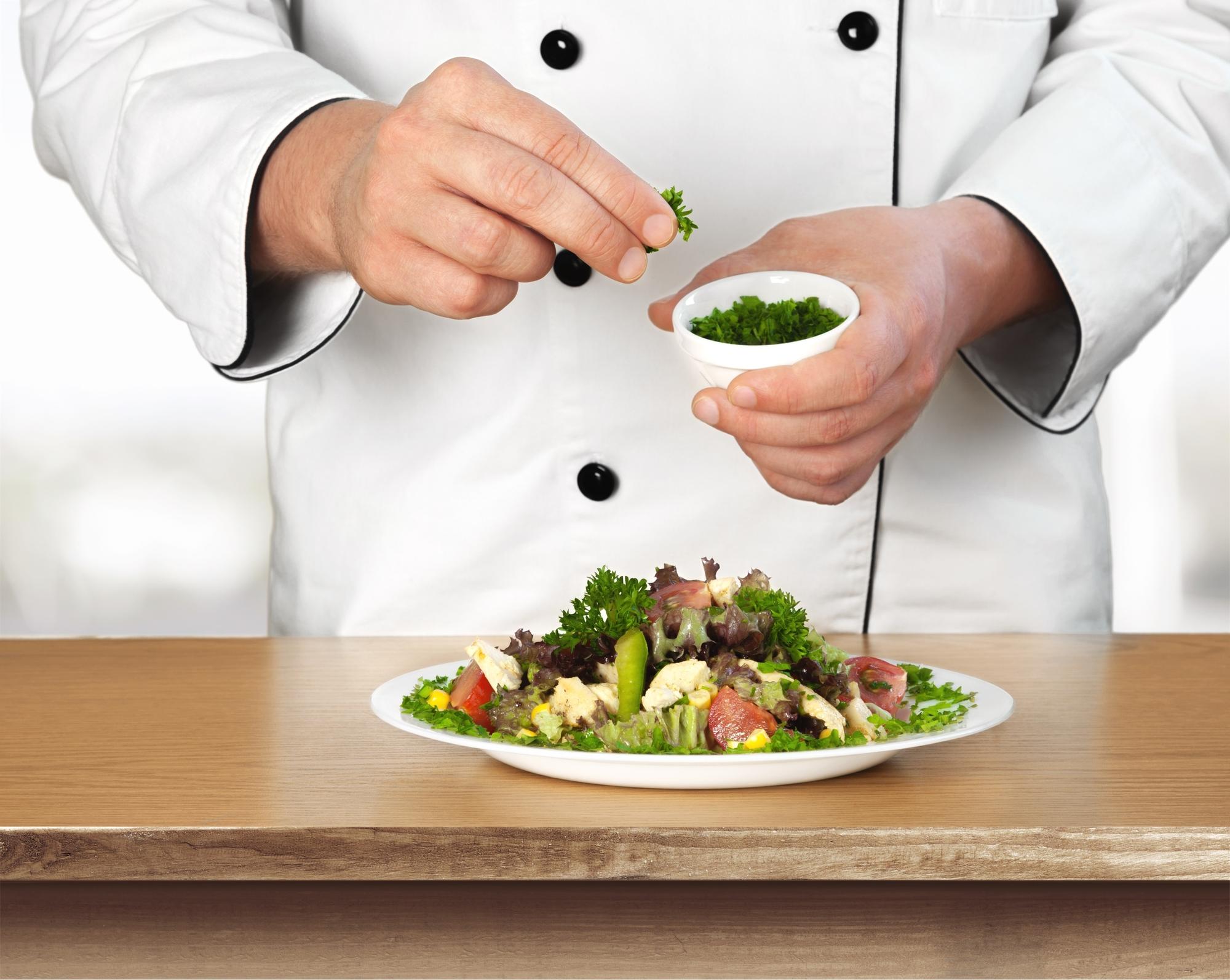 Chef arranging plated meal from a kit on a small kitchen island